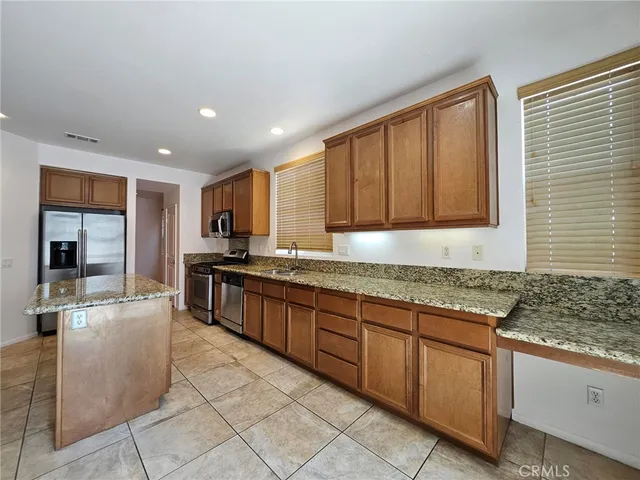 a large kitchen with granite countertop a sink and white cabinets