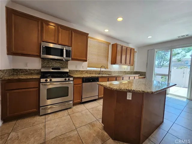 a kitchen with stainless steel appliances granite countertop a stove a sink dishwasher a microwave oven and a refrigerator