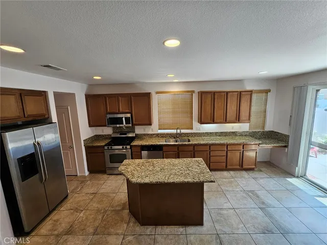 a kitchen with a stove a sink dishwasher a refrigerator and a oven with wooden cabinets