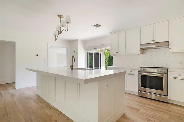 a kitchen with white cabinets and wooden floor