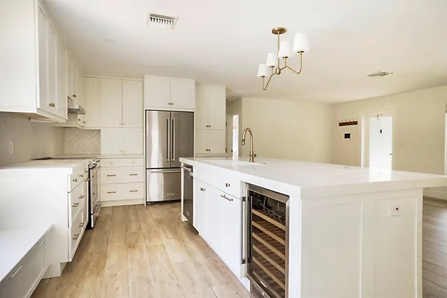 a kitchen with white cabinets and large window