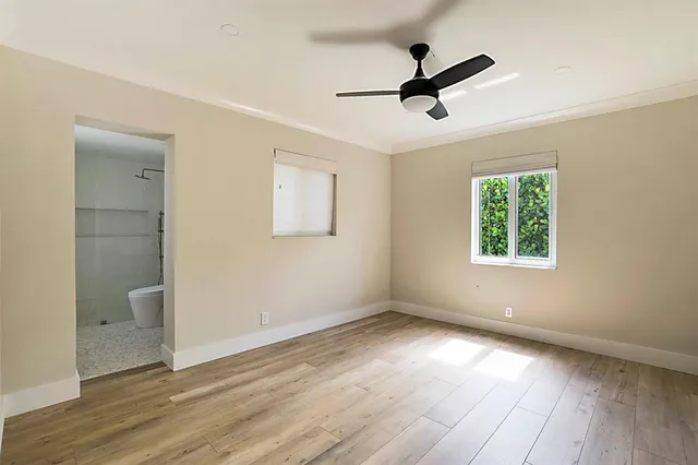 a view of empty room with wooden floor and fan