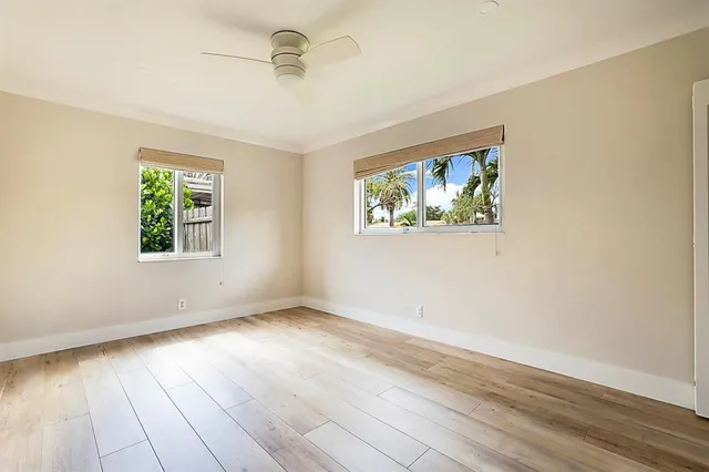 an empty room with wooden floor cabinet and windows