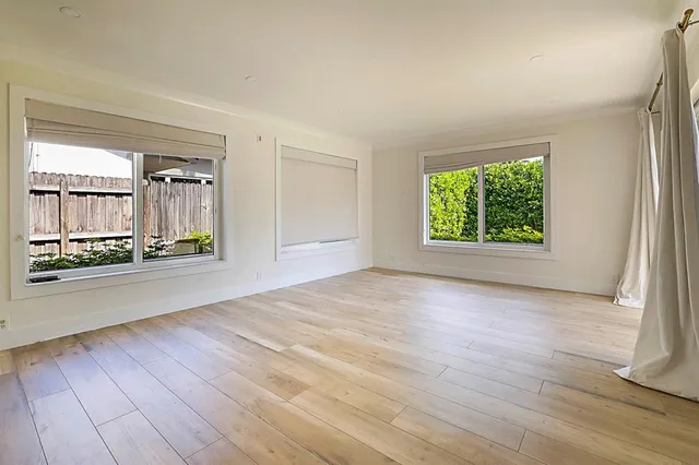 a view of a big room with wooden floor and windows