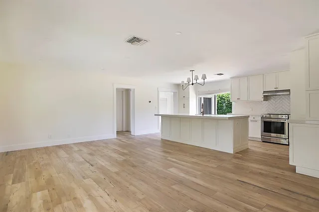 a view of a kitchen with kitchen island wooden floor appliances and cabinets
