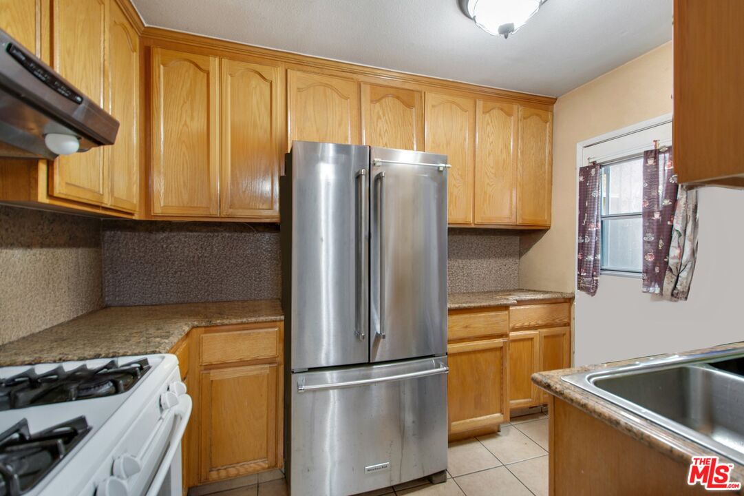 4713 Clinton Street Los Angeles, CA 90004 - Photo 14 of 25 a kitchen with stainless steel appliances granite countertop a refrigerator and a stove top oven