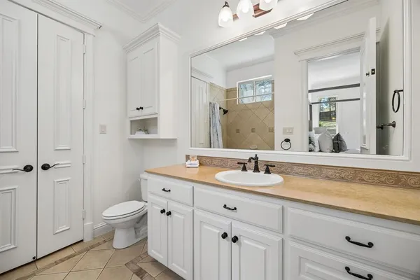 a bathroom with a granite countertop sink a toilet and a mirror