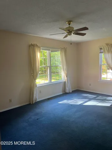 an empty room with windows and fan