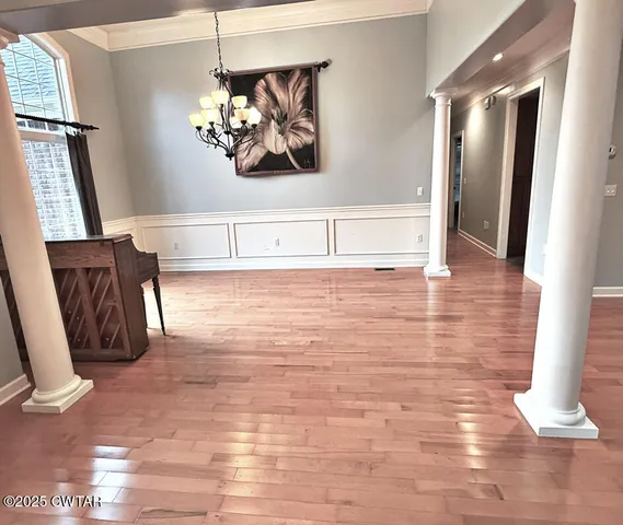a view of a hallway with wooden floor and a chandelier