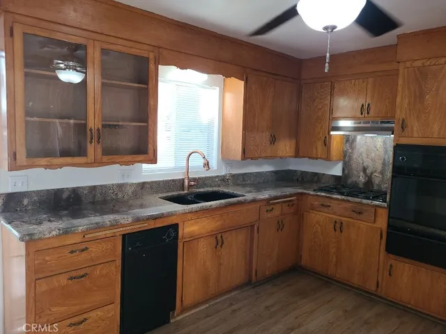 a kitchen with stainless steel appliances granite countertop a sink a stove and wooden cabinets