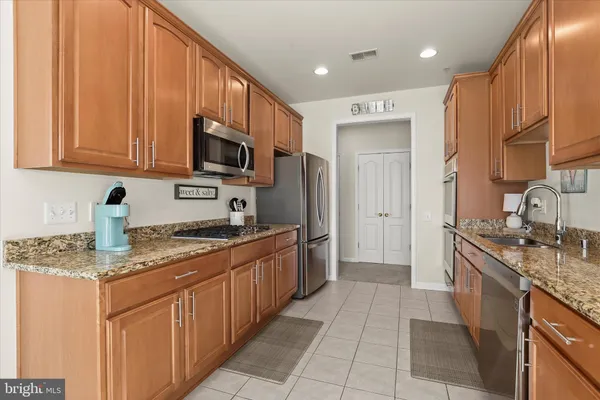 a kitchen with stainless steel appliances kitchen island granite countertop a stove top oven a sink and a microwave