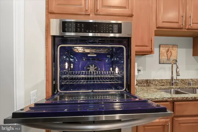 a kitchen with stainless steel appliances granite countertop a stove top oven a sink a dining table and chairs with wooden floor