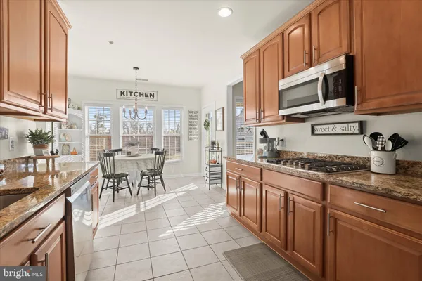 a kitchen with stainless steel appliances granite countertop a stove top oven a sink a dining table and chairs