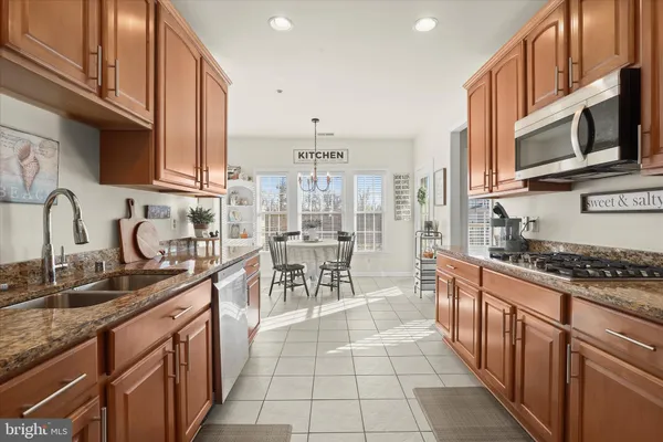a kitchen with granite countertop a table chairs a sink dishwasher refrigerator and cabinets