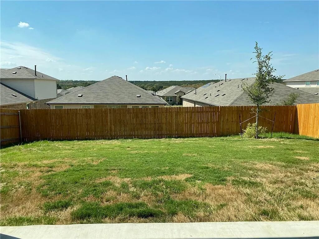 10612 Gonzales Ranger Pass Austin, TX 78754 - Photo 19 of 19 A wooden fence encloses the grassy yard, offering views of the surrounding neighborhood rooftops.