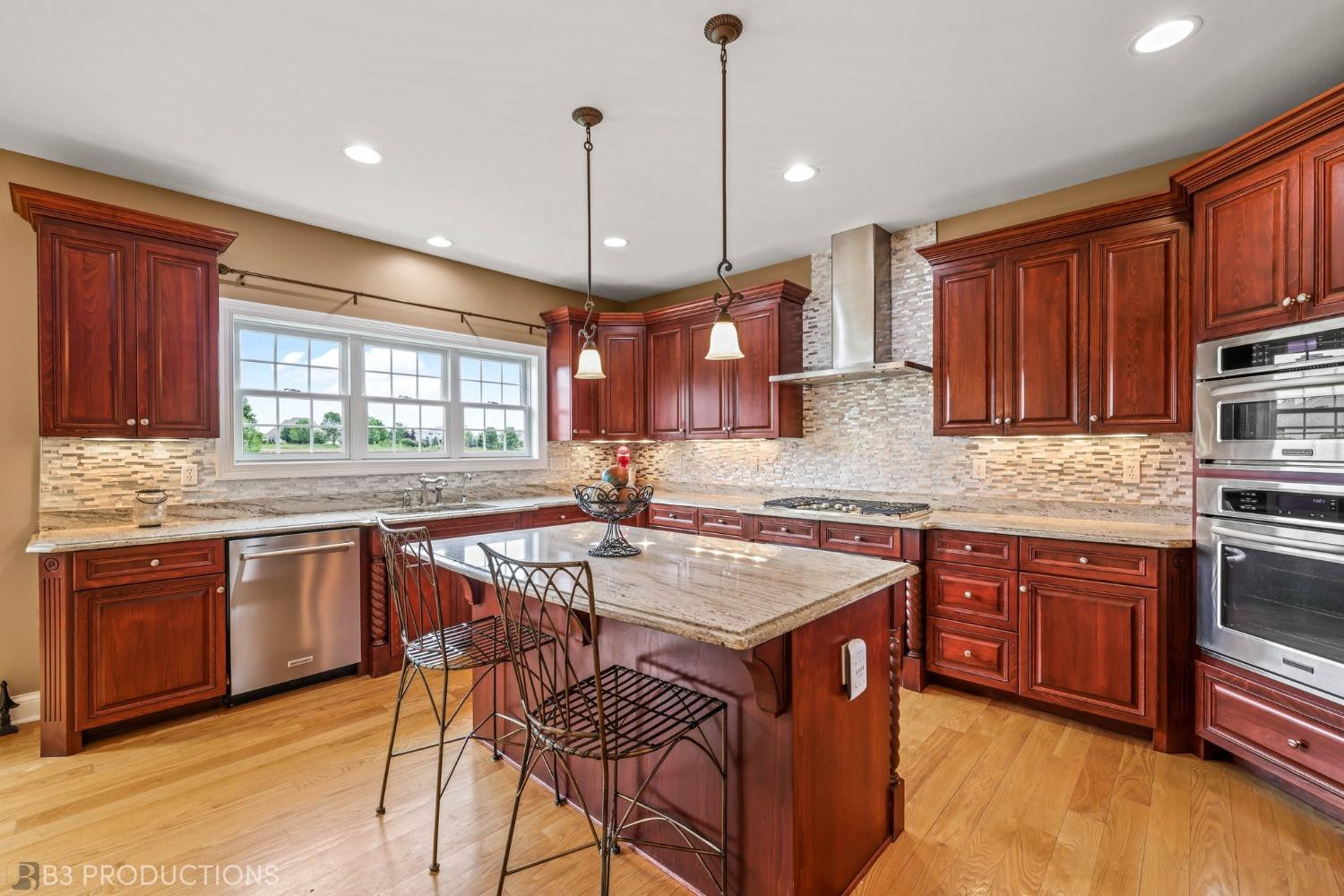 1825 Bramble Trace Chesterton, IN 46304 - Photo 10 of 30 a kitchen with stainless steel appliances granite countertop wooden cabinets a sink a stove a dining table and chairs