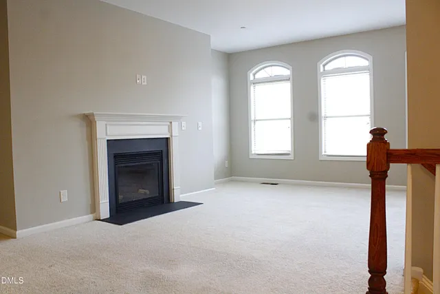 an empty room with windows and fireplace