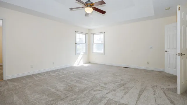 an empty room with windows and chandelier fan