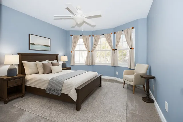 a view of a white house with potted plants and a large tree