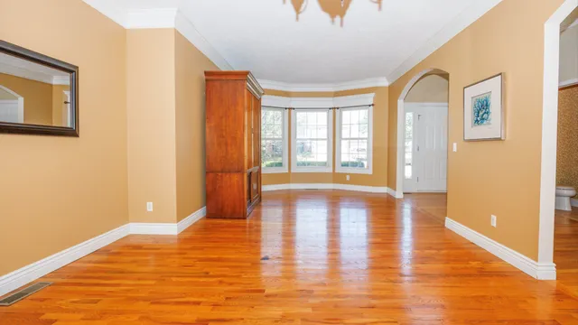 a view of an empty room with a window and wooden floor