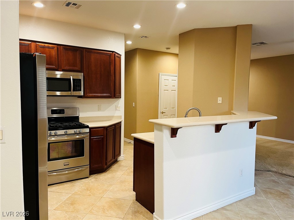 259 Integrity Ridge Drive Henderson, NV 89052 - Photo 11 of 50 Kitchen w/breakfast bar w/corian counters, cherry cabinets, SS appliances, tile floors, new sink & faucet, dining nook & pantry.
