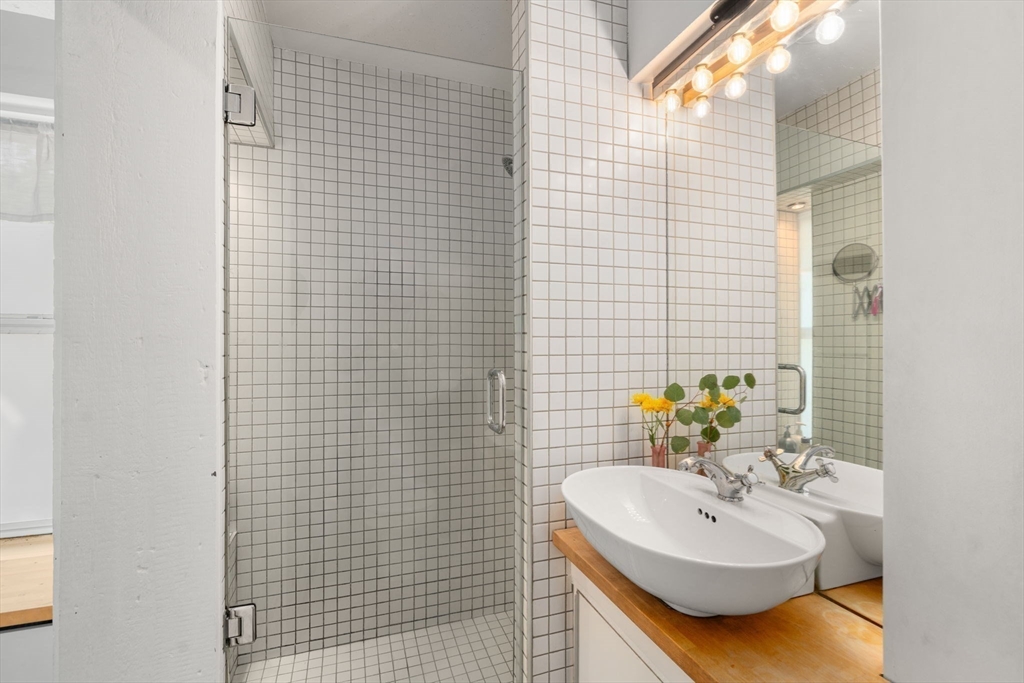 67 Dudley Street, Unit SF Boston, MA 02119 - Photo 12 of 28 a bathroom with a sink a mirror and shower