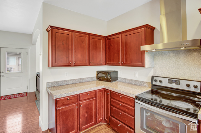 4 Hanauer Place Murray, UT 84107 - Photo 12 of 24 Kitchen with stainless steel electric range, wall chimney exhaust hood, black microwave, light countertops, and light wood finished floors