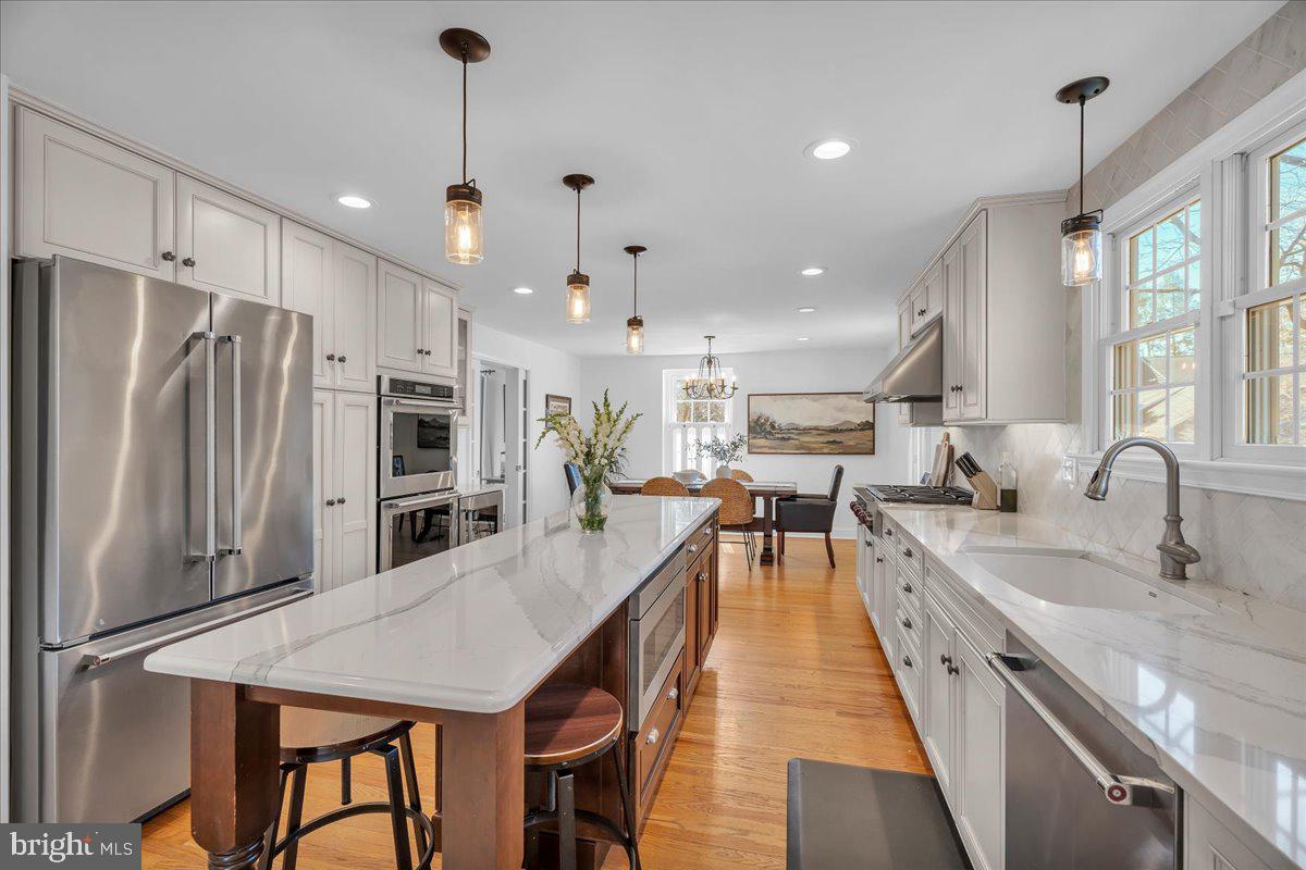 126 Ashford Road Cherry Hill, NJ 08003 - Photo 13 of 43 a kitchen with stainless steel appliances kitchen island granite countertop a refrigerator a sink dishwasher a stove and a dining table with wooden floor