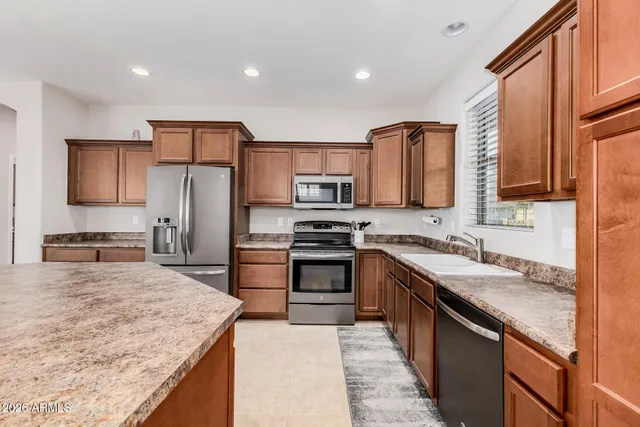 a kitchen with stainless steel appliances granite countertop a sink stove microwave and refrigerator