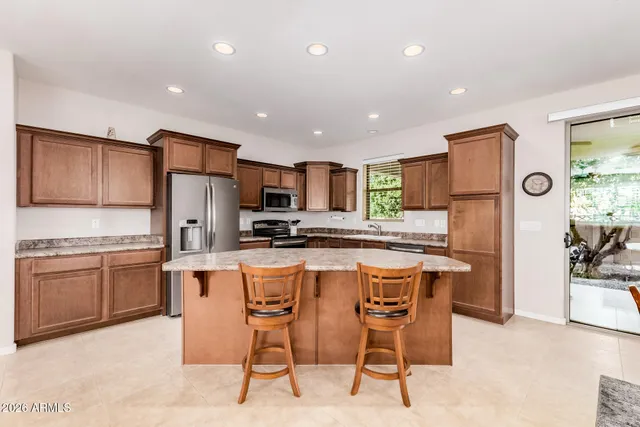 a kitchen with stainless steel appliances kitchen island granite countertop a refrigerator and a stove top oven