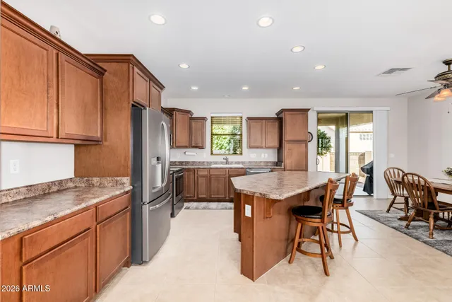 a kitchen with stainless steel appliances granite countertop table chairs sink refrigerator and cabinets