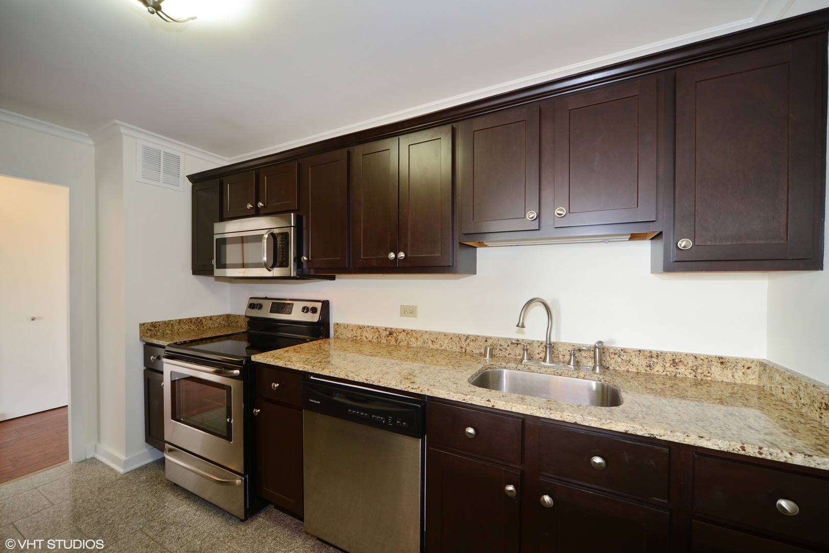 5455 North Sheridan Road, Unit 2810 Chicago, IL 60640 - Photo 3 of 9 a kitchen with granite countertop wooden cabinets and a sink