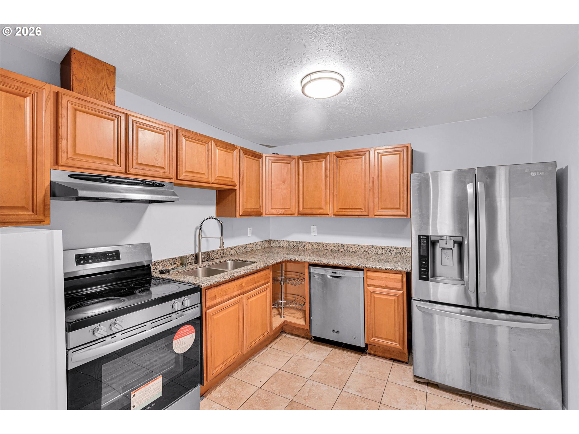 14125 Southeast Division Street Portland, OR 97233 - Photo 8 of 17 a kitchen with stainless steel appliances granite countertop a refrigerator sink and cabinets