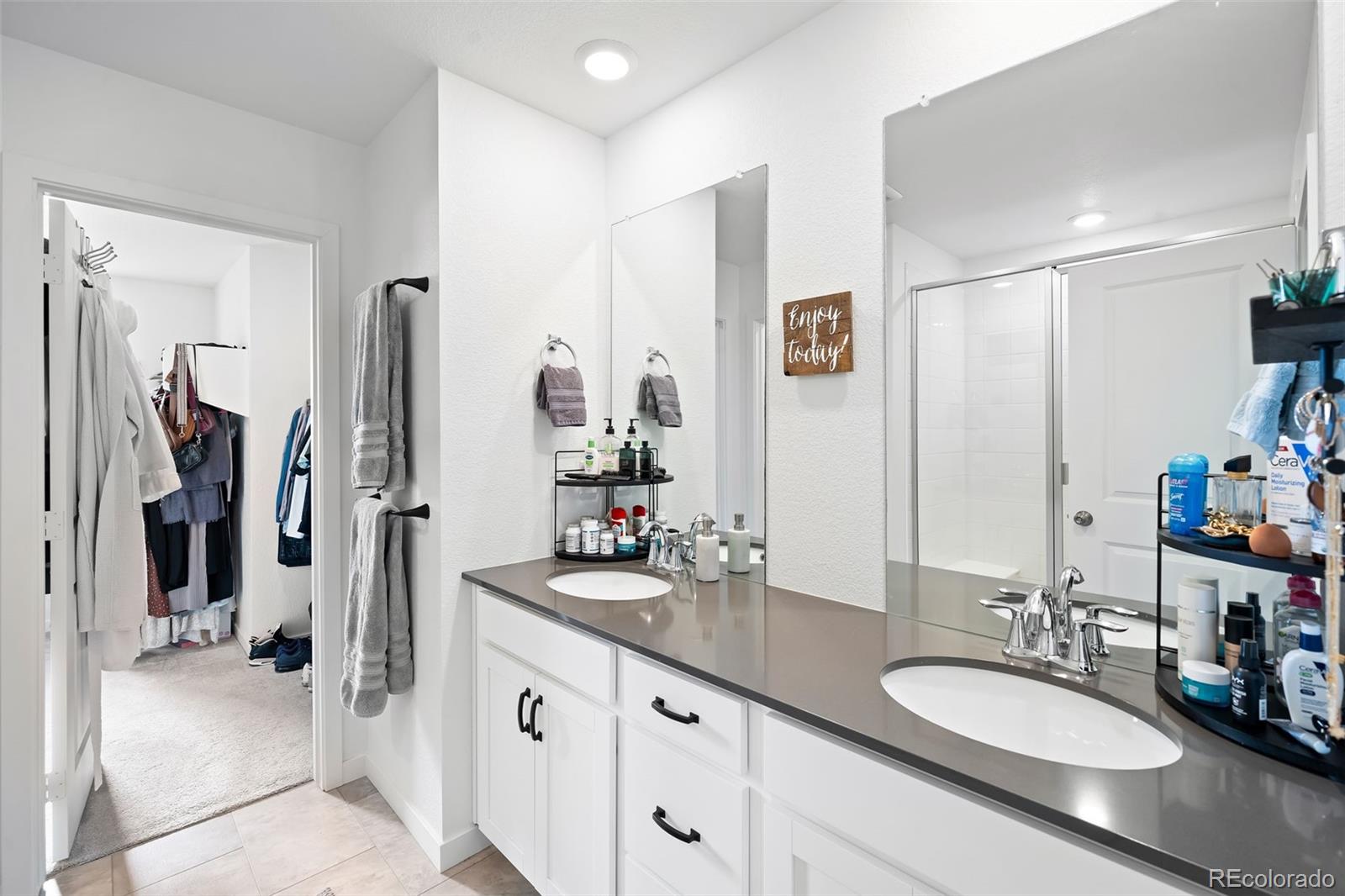 16249 Laurentide Place Parker, CO 80134 - Photo 17 of 30 a bathroom with double vanity sinks a vanity two mirror and shower