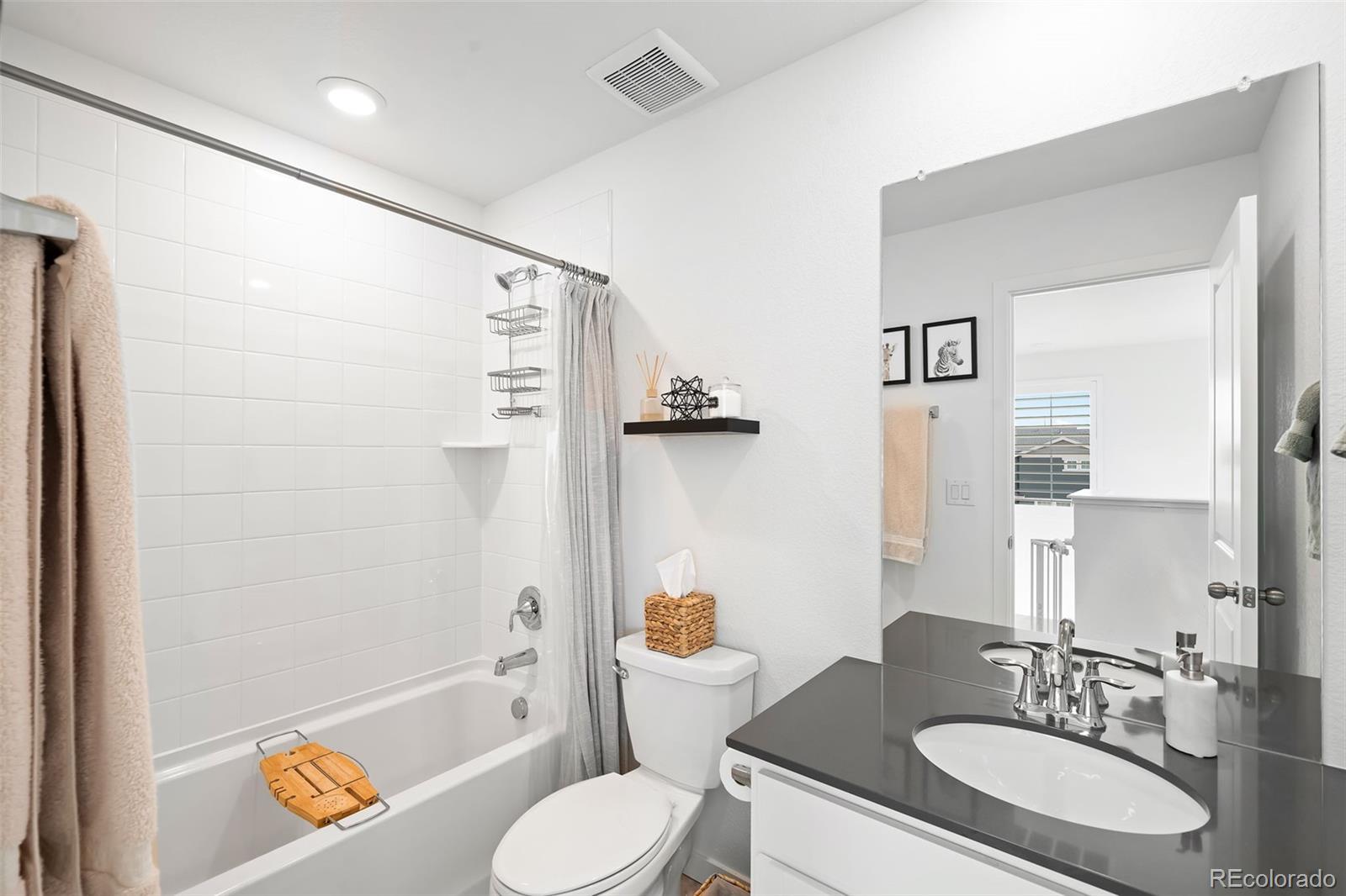 16249 Laurentide Place Parker, CO 80134 - Photo 20 of 30 a bathroom with a granite countertop sink toilet a mirror a bathtub and shower