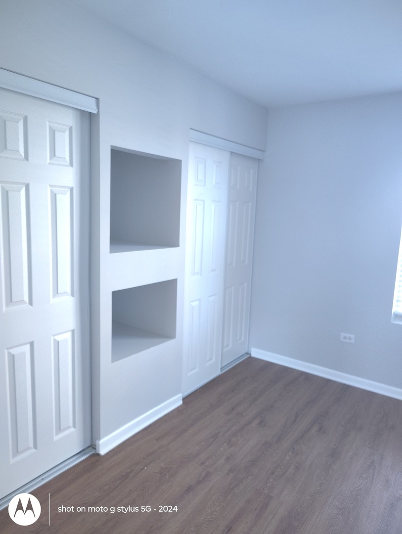 2367 East 70th Place, Unit 1A Chicago, IL 60649 - Photo 18 of 30 a view of an empty room with wooden floor and a window