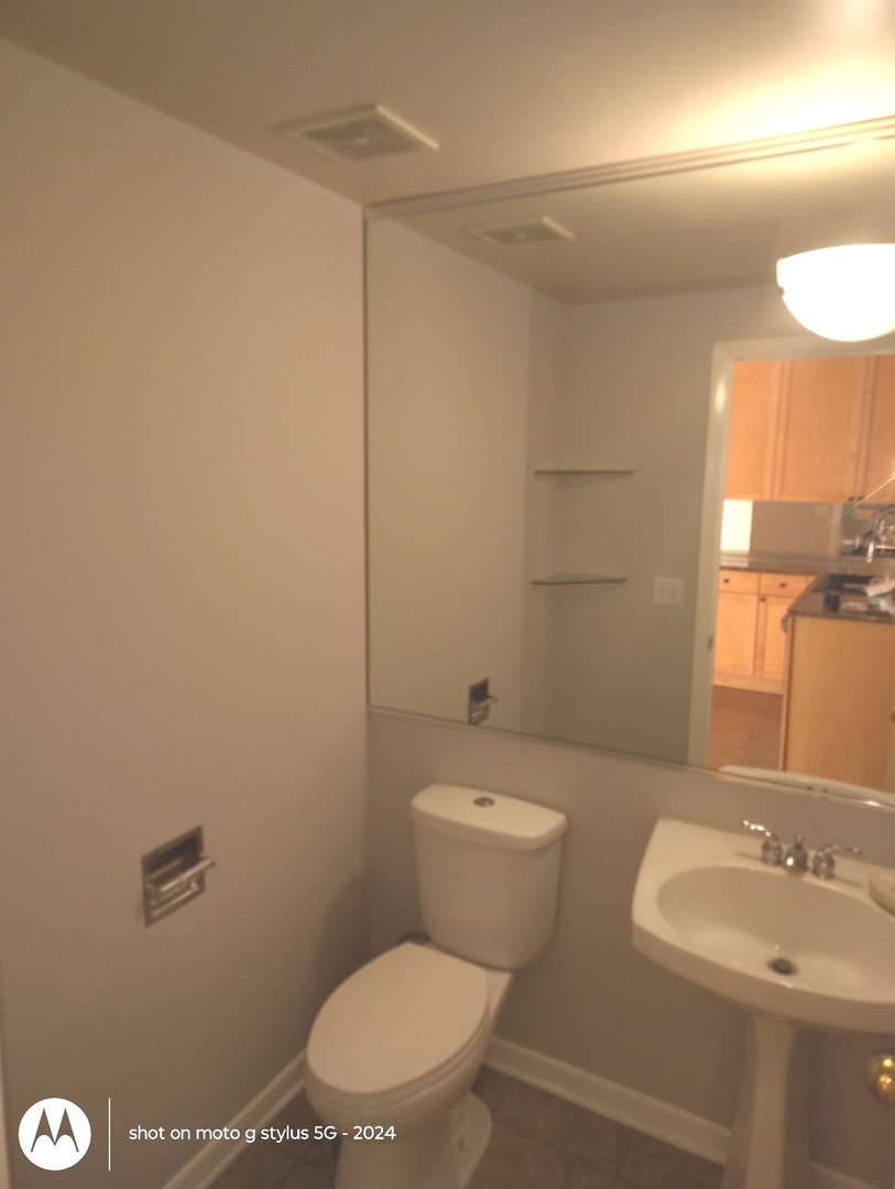 2367 East 70th Place, Unit 1A Chicago, IL 60649 - Photo 8 of 30 a bathroom with a toilet a sink and mirror