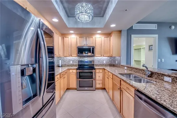 a kitchen with stainless steel appliances granite countertop a refrigerator a stove and a sink