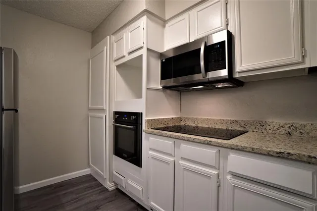 a kitchen with stainless steel appliances granite countertop white cabinets and microwave