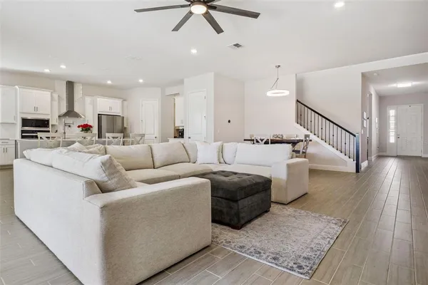 a kitchen with stainless steel appliances a refrigerator a stove a sink and white cabinets with wooden floor