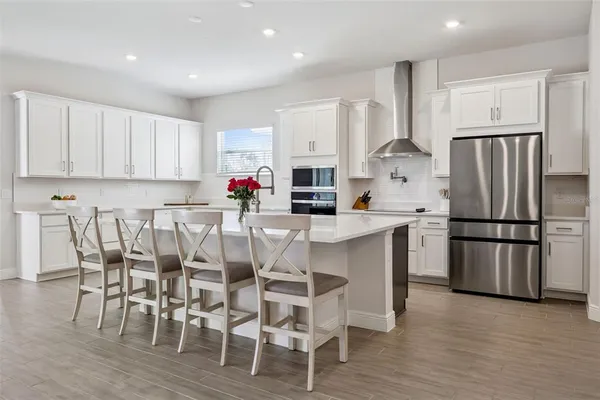 a kitchen with stainless steel appliances a dining table chairs and wooden floor