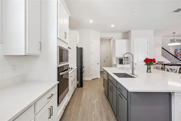 a kitchen with stainless steel appliances a dining table chairs microwave and sink