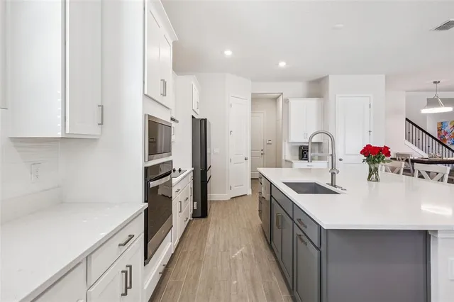 a kitchen with stainless steel appliances a dining table chairs microwave and sink