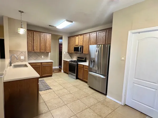 a kitchen with stainless steel appliances kitchen island granite countertop a refrigerator a stove a sink and a stove