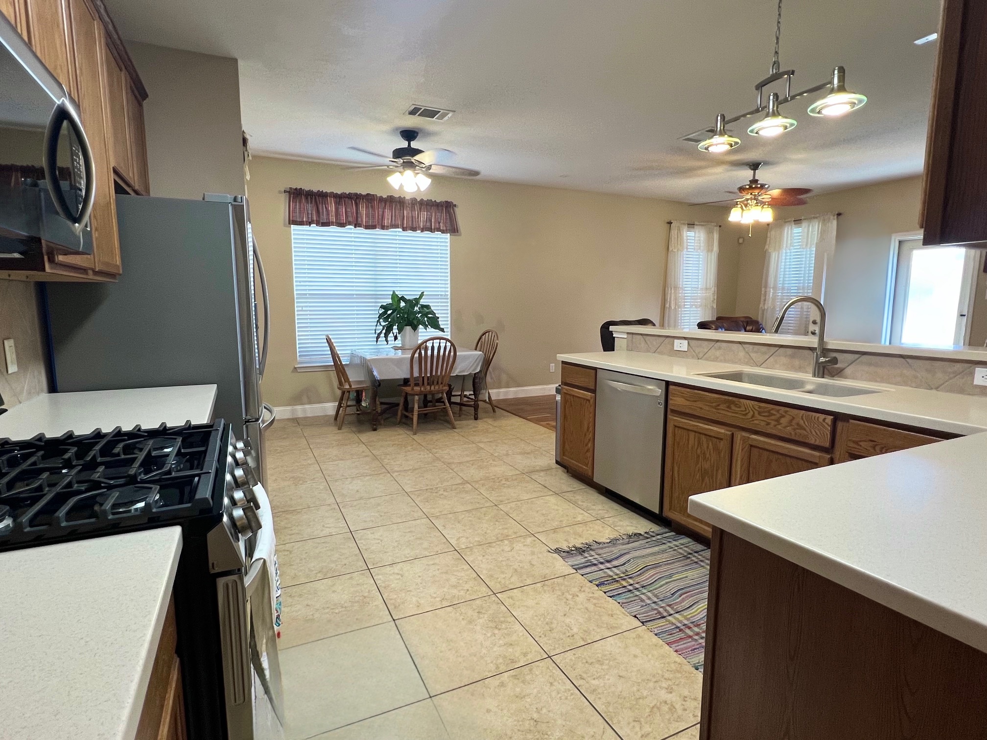17705 Mahonia Lane Elgin, TX 78621 - Photo 10 of 35 Kitchen featuring stainless steel appliances, a ceiling fan, light countertops, and wood finish cabinetry