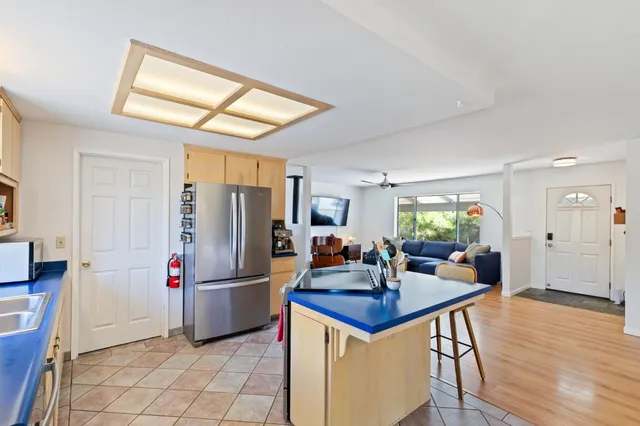 a kitchen with stainless steel appliances granite countertop a stove a refrigerator a dining table and chairs with wooden floor