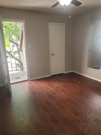 an empty room with wooden floor cabinet and windows