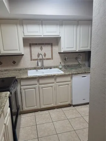 a kitchen with granite countertop a sink a stove and cabinets