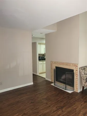 a view of an empty room with wooden floor fireplace and a window