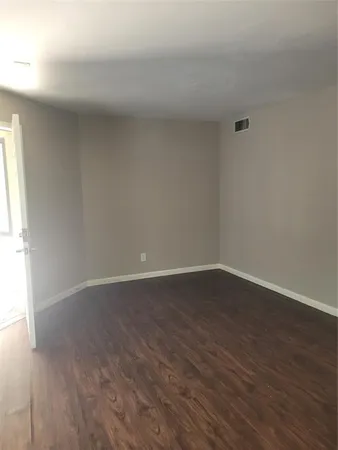 a view of an empty room and wooden floor and a window
